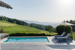 a swimming pool with a chair and an umbrella at PanoramaLodge Samerberg in Samerberg