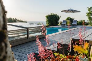 a pool with two chairs and an umbrella on a deck at PanoramaLodge Samerberg in Samerberg