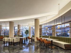 a restaurant with tables and chairs in a building at Movenpick by Accor Qingdao Sunmei in Qingdao