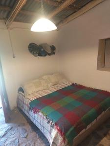 a bedroom with a bed with a colorful blanket at Hostal Rústico Las Pircas in Alcoguaz +10 photos