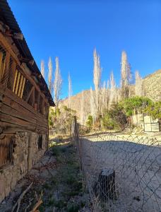 a fence next to a building with trees in the background at Hostal Rústico Las Pircas in Alcoguaz