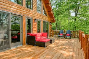 a screened in porch of a log cabin with red furniture at Deep Creek Mountain Retreat in McHenry