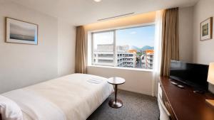 a hotel room with a bed and a large window at Hotel Mielparque Kumamoto in Kumamoto