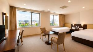 a hotel room with two beds and a desk and a table at Hotel Mielparque Kumamoto in Kumamoto