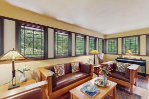 a living room with leather couches and a piano at The Frank Lloyd Wright Home @ Deep Creek, MD in Bittinger +21 photos