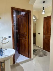 a bathroom with a wooden door and a sink at Jannat Résidence in Ouarzazate