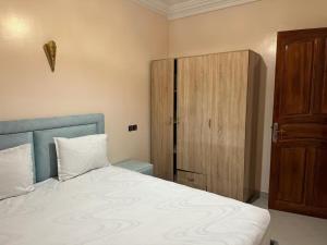 a bedroom with a bed and a wooden cabinet at Jannat Résidence in Ouarzazate