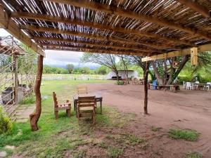 a picnic table and benches under a wooden pavilion at Hospedaje Tidae in Tinogasta