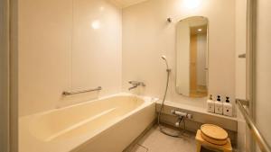 a white bathroom with a tub and a mirror at Hotel Mielparque Kumamoto in Kumamoto +32 photos