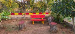 a red chair sitting on logs in a garden at Surya farms in Rajiv Gandhi International Airport +2 photos