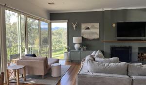 a living room with couches and a tv and a fireplace at The River House in Merrijig