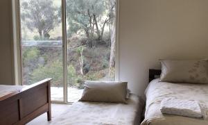 a bedroom with two beds and a large window at The River House in Merrijig