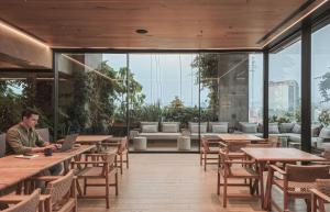 a man sitting at a table with a laptop in a restaurant at University Tower by Kukun Apartments in Mexico City