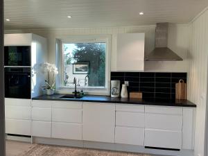 a kitchen with white cabinets and a sink and a window at Cozy Home in Sortland in Sortland