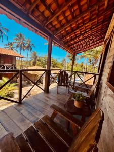 a porch with two wooden chairs and a table at Maré de Atins Eco Lodge in Atins