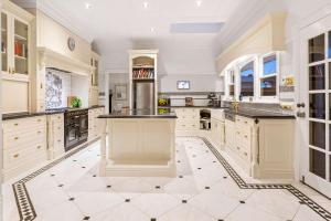 a large kitchen with white cabinets and black counter tops at Kirinaran Manor Pool & Bar Room in Frankston South