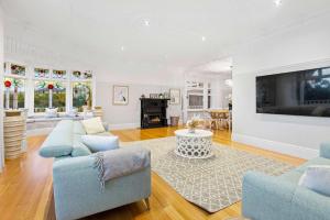 a living room with two blue chairs and a tv at Kirinaran Manor Pool & Bar Room in Frankston South
