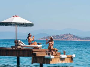 three women sitting on a dock in the water at Hyde Bodrum - Ultra All Inclusive, Adult Only in Torba