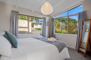 a bedroom with a bed and a large window at Tideview Cottage - Incredible Views - Tairua in Tairua