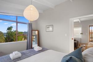 a bedroom with a bed and a large window at Tideview Cottage - Incredible Views - Tairua in Tairua