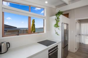 a kitchen with white counters and a large window at Tideview Cottage - Incredible Views - Tairua in Tairua