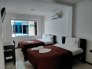 a hotel room with two beds and a window at Hotel Los Potrillos in Aguazul