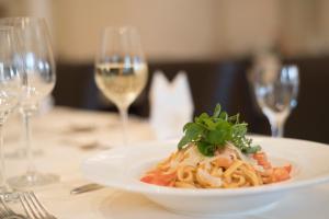 a plate of pasta on a table with wine glasses at Hotel Wilhelmshöhe Auderath in Auderath