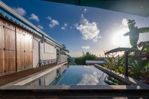 a swimming pool next to a house with the sky at Combava à Marie Galante in Grand-Bourg
