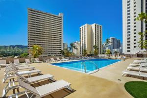 a swimming pool with lounge chairs and buildings at Aston at the Waikiki Banyan in Honolulu