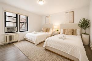 two beds in a bedroom with white walls and windows at Bay Ridge ApartHotel in Brooklyn