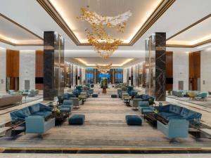 a large lobby with blue couches and a chandelier at Rixos Premium Alamein in El Alamein