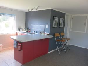 a kitchen with a red and blue counter and chairs at Atalaya in Waihi Beach