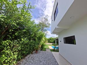 a backyard with a white house and a hedge at Villa Kas Abao Doradal Ant in Doradal