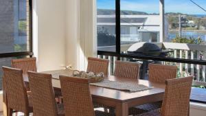 a dining room table and chairs with a view of a balcony at The Escape in Merimbula +15 photos