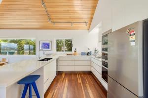 a kitchen with white cabinets and a wooden ceiling at Bula Vista in Merimbula