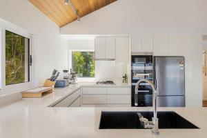 a white kitchen with a sink and a refrigerator at Bula Vista in Merimbula