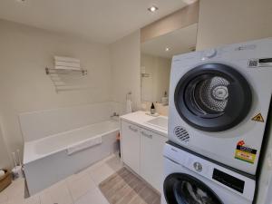 a washing machine in a white bathroom with a sink at Marley s Place in Queenscliff