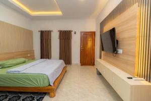 a bedroom with a bed and a flat screen tv at Heyho Homestay Maluk in Maluk +2 photos