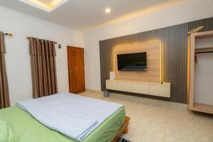 a bedroom with a bed and a flat screen tv at Heyho Homestay Maluk in Maluk