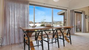 a dining room with a table and chairs and a large window at PiPis on Collins in Merimbula