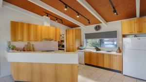 a kitchen with wooden cabinets and a white refrigerator at PiPis on Collins in Merimbula +18 photos