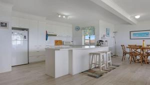 a white kitchen with a counter and a table at Quarterdeck 3 in Tura Beach