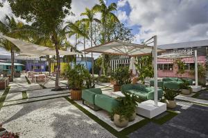 a patio with couches and umbrellas and palm trees at The 27 Wynwood in Miami