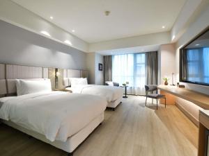 a hotel room with two beds and a flat screen tv at Mercure Qidong Downtown in Qidong +72 photos