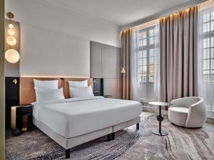 a bedroom with a large white bed and a chair at Mövenpick Grand Hotel Wroclaw in Wrocław