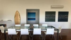 a dining room with a glass table and white chairs at Turaroo in Tura Beach