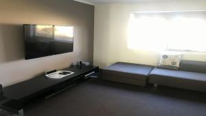 a living room with a couch and a flat screen tv at Turaroo in Tura Beach