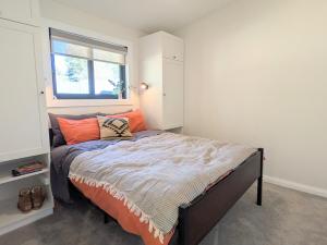 a bedroom with a bed with orange pillows and a window at Elm's Deep Guest House in Berridale