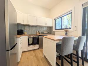 a kitchen with white cabinets and a table and chairs at Elm's Deep Guest House in Berridale