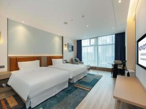 a hotel room with two beds and a flat screen tv at Novotel Wuxi in Wuxi